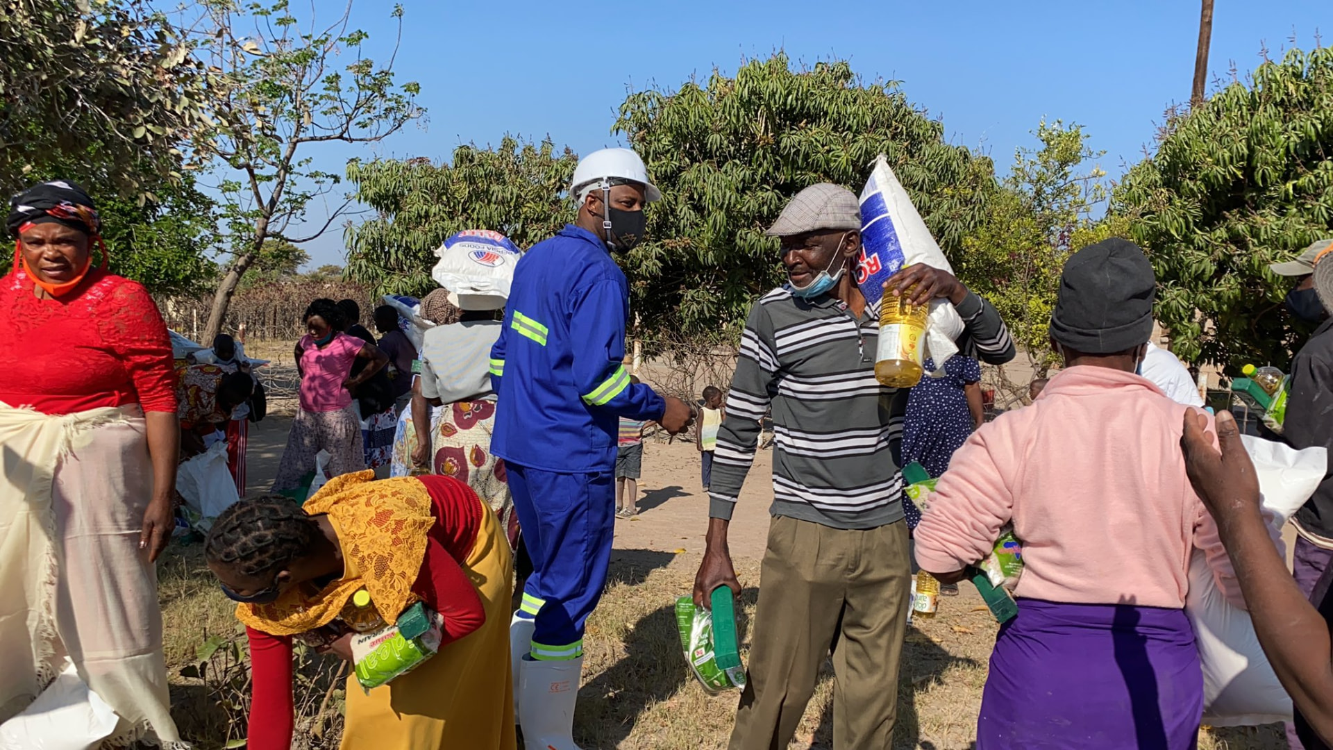 Volunteers handing out food and cooking oil at a community distribution