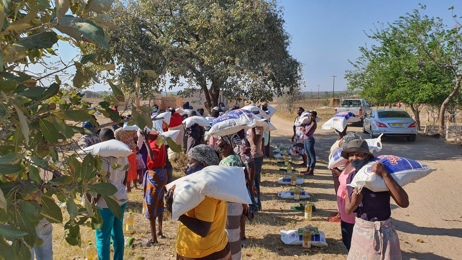 Families queueing along a rural road for food aid